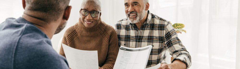 pro-bono-lawyer-clients | Legal professional providing pro bono consultation to senior couple reviewing estate planning documents in bright office setting